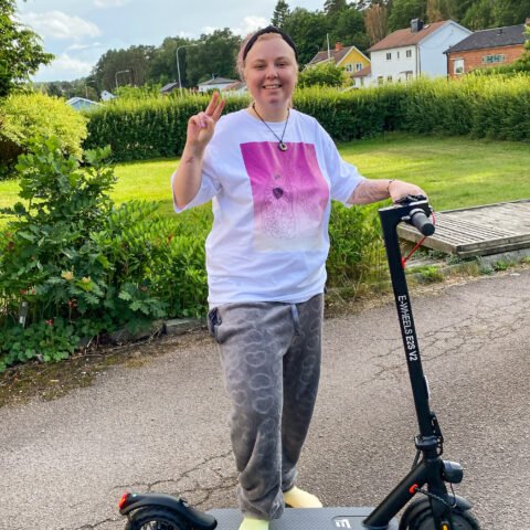 En tjej som heter ida sår på en elskoter med ett stort leende på läpparna